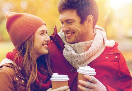 happy couple with coffee walking in autumn park