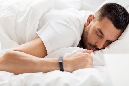 man with smartwatch sleeping in bedの写真素材