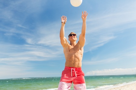 young man with ball playing volleyball on beachの写真素材