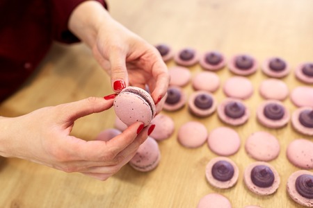 chef sandwiching macarons shells with cream