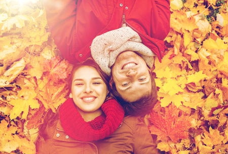 close up of smiling couple lying on autumn leavesの写真素材