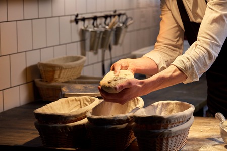 baker with rising in baskets at bakeryの写真素材