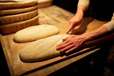 chef or baker with cooking bread at bakery