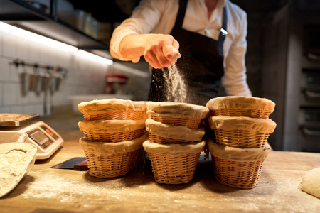 baker with baskets for dough rising at bakeryの写真素材