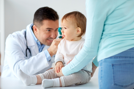 medicine, healthcare, pediatry and people concept - otolaryngologist or doctor checking baby ear with otoscope and young woman at clinicの写真素材