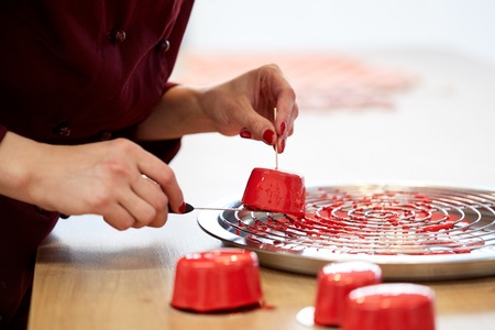 cooking, baking and confectionery concept - chef serving mirror glaze cakes at pastry shopの写真素材