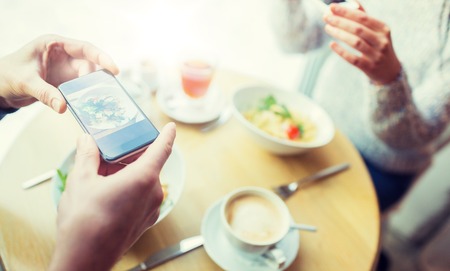 close up of couple picturing food by smartphone