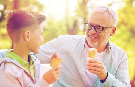 Old man and boy eating ice cream at summer parkの写真素材