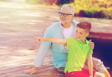 grandfather and grandson sitting on river berthの写真素材