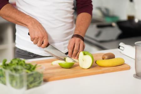 man chopping fruits and cooking at home kitchenの写真素材