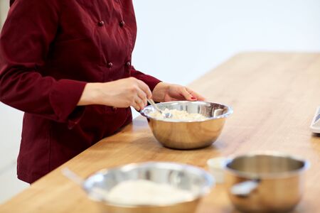 chef with flour in bowl making batter or doughの写真素材