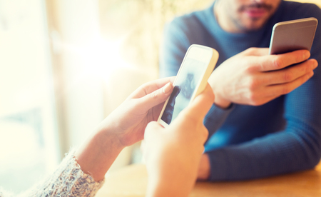 close up of couple with smartphones at cafeの写真素材