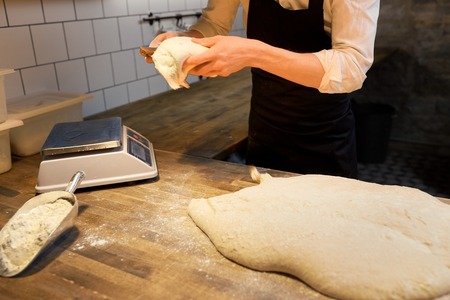 baker portioning dough with bench cutter at bakeryの写真素材
