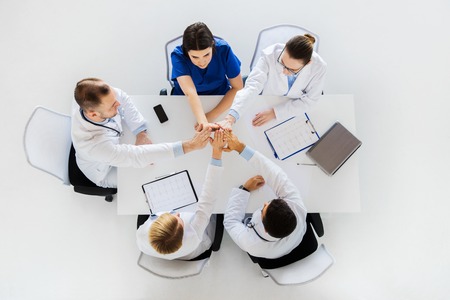 group of doctors making high five at tableの写真素材