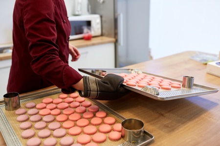 chef with macarons on oven tray at confectioneryの写真素材