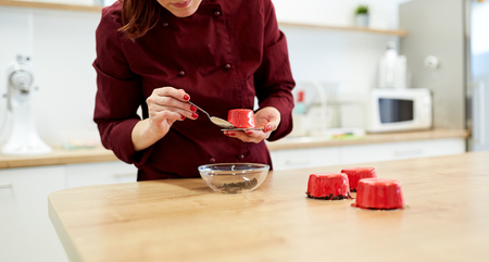 chef decorating mirror glaze cakes at pastry shopの写真素材