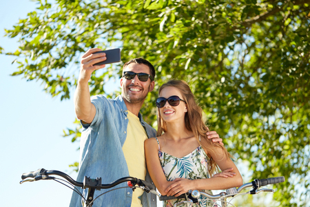 couple with bicycles taking selfie by smartphoneの写真素材