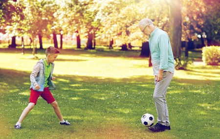 family, generation, game, sport and people concept - happy grandfather and grandson playing football...
