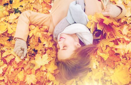 beautiful happy woman lying on autumn leavesの写真素材