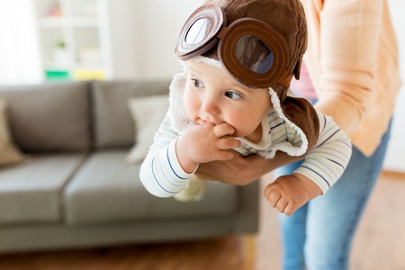happy mother with baby wearing pilot hat at homeの写真素材
