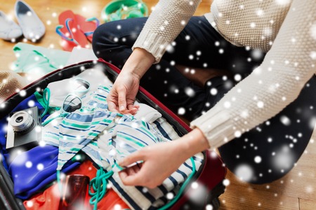 close up of woman packing travel bag for vacation