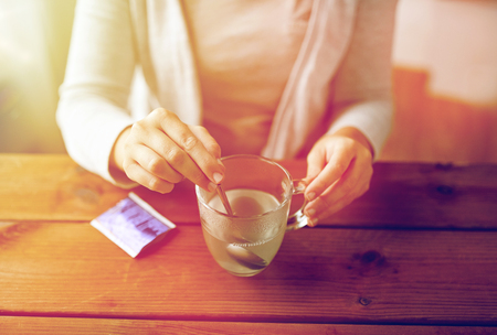 woman stirring medication in cup with spoonの写真素材