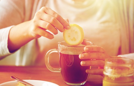 close up of woman adding lemon to tea with honeyの写真素材