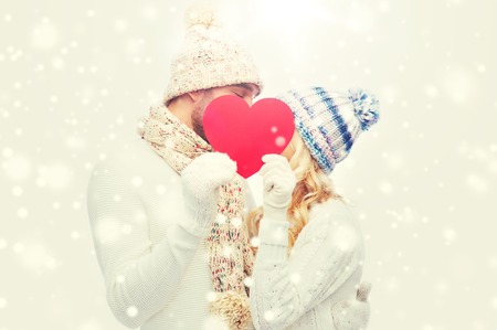 smiling couple in winter clothes with red heartの写真素材