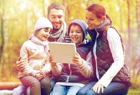 family sitting on bench with tablet pc at camp