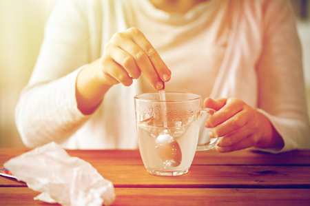 woman stirring medication in cup with spoonの写真素材