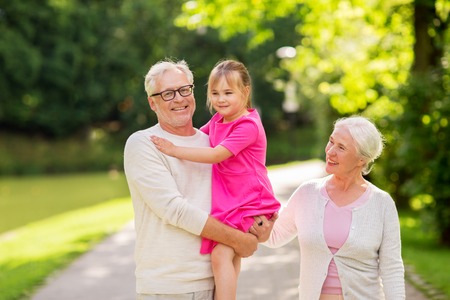 senior grandparents and granddaughter at parkの写真素材