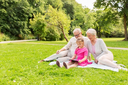 grandparents and granddaughter with tablet pcの写真素材