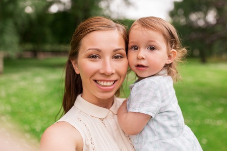 mother with baby girl taking selfie at summer parkの写真素材