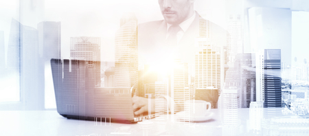 business, technology and internet concept - businessman with laptop computer and coffee at office over city background and double exposure effectの写真素材