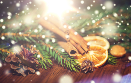 decoration, winter, holidays and new year concept - close up of christmas fir branch with cinnamon and dried orange on wooden tableの写真素材