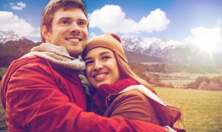 tourism, travel and people concept - happy young couple hugging over alps mountains background