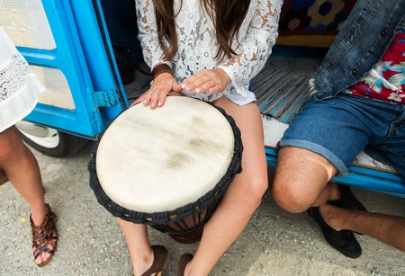 summer holidays, music, travel and people concept - close up of hippie woman with friends having fun and playing tom-tom drum over minivan carの写真素材
