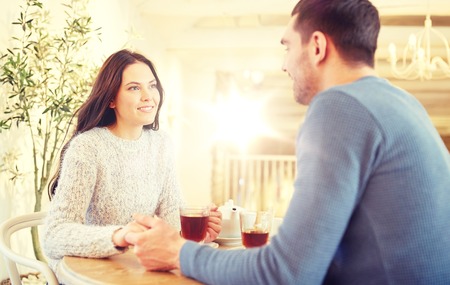 happy couple with tea holding hands at restaurantの写真素材