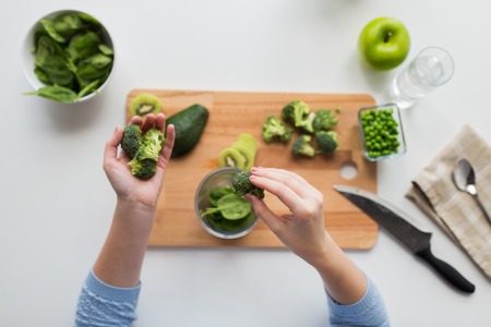 woman hand adding broccoli to measuring cup