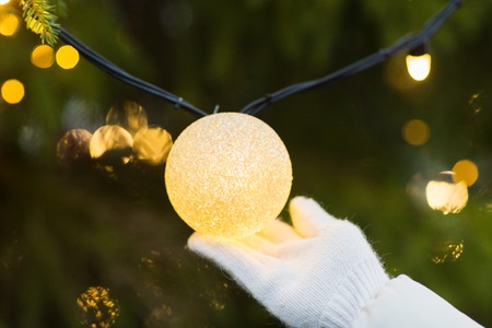 close up of hand with christmas tree garland bulb