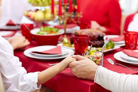 family having holiday dinner and praying at homeの写真素材