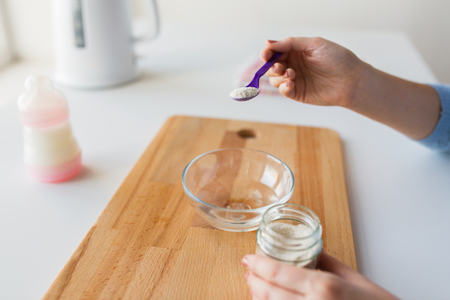 hands with spoon and jar making baby cerealの写真素材