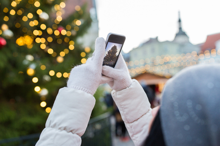 hands with smartphone photographing christmas treeの写真素材