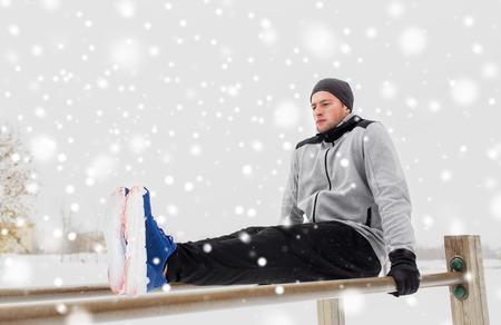 young man exercising on parallel bars in winter