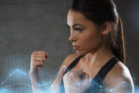 sport, fitness, martial arts and people concept - woman holding fists and fighting in gymの写真素材