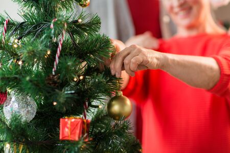 close up of senior woman decorating christmas treeの写真素材
