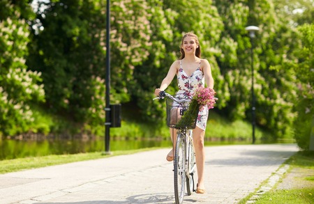 happy woman riding fixie bicycle in summer parkの写真素材
