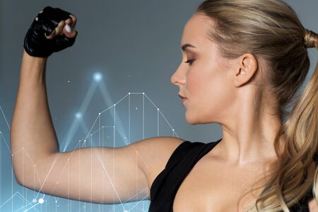 close up of woman posing and showing biceps in gymの写真素材