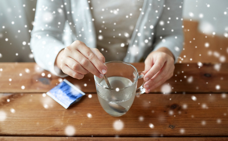 ill woman stirring medication in cup with spoonの写真素材
