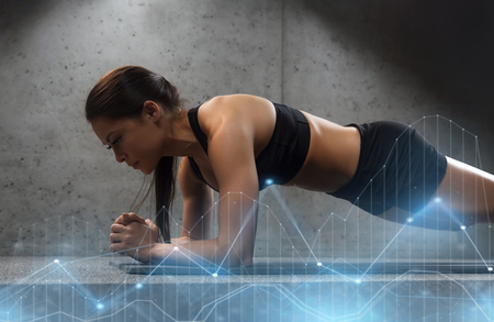 woman doing plank exercise on mat in gymの写真素材